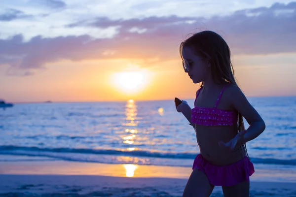 Kleines entzückendes Mädchen, das im Sonnenuntergang an einem tropischen Strand spaziert — Stockfoto