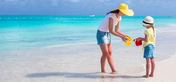 Tropik sahilde oynarken küçük sevimli kız ve genç anne — Stok fotoğraf