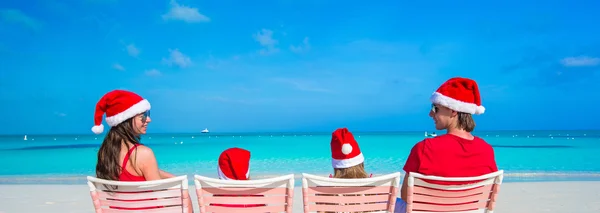 Счастливая семья в рождественских шляпах веселится на белом пляже — стоковое фото