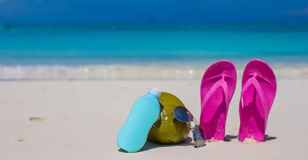 Flip flops, καρύδα και suncream σχετικά με λευκή άμμο — Φωτογραφία Αρχείου