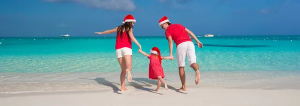 Happy family of three in Christmas Hats having fun on white beach — Stock Photo, Image