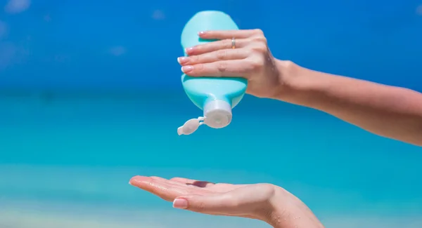 Vrouw handen zetten zonnebrandcrème uit een zonnebrandfles — Stockfoto