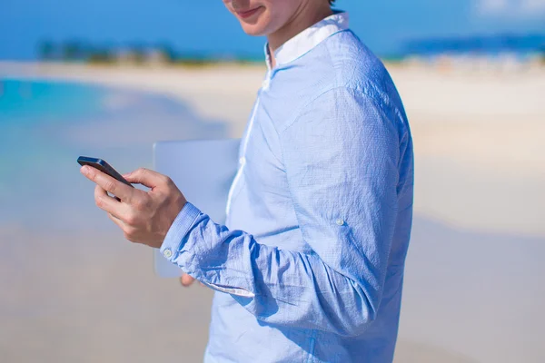 Telefon w męskiej ręki na tropikalnej plaży z bliska — Zdjęcie stockowe