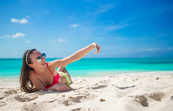 Beautiful young woman taking a photo herself on tropical beach — Stock Photo, Image