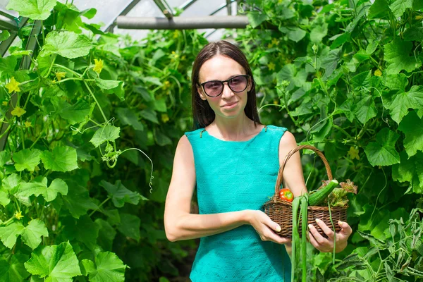 Jeune femme tenant un panier de verdure et d'oignon dans la serre — Photo