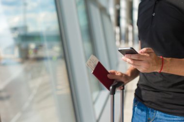 Man holding cep telefonu, Pasaportlar ve uçuş bekleyen Havaalanı'nda yatılı pasaportu