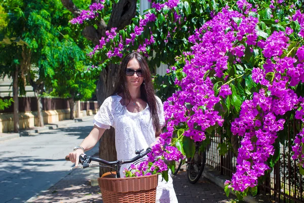 Young woman on summer vacation biking at blossoming street — Stock Photo, Image