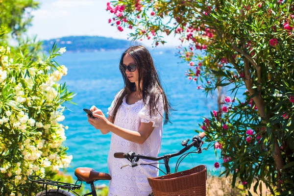 年轻女子用手机背景美丽的海湾 — 图库照片