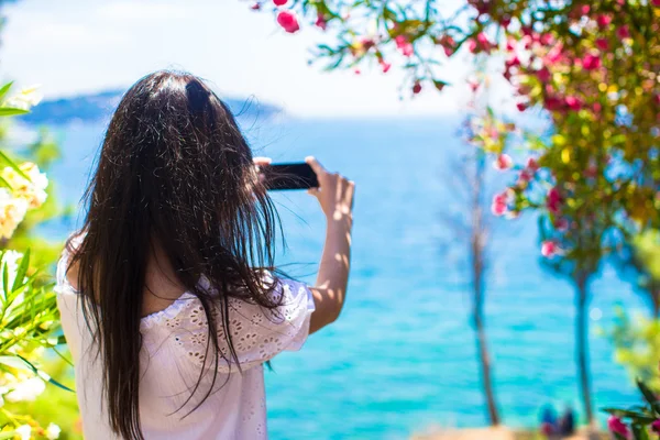 Vista posterior de la mujer joven tomando fotos con el teléfono en la hermosa bahía — Foto de Stock