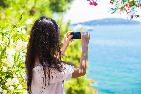 后视图在美丽的海湾上用手机拍照的年轻女子 — 图库照片