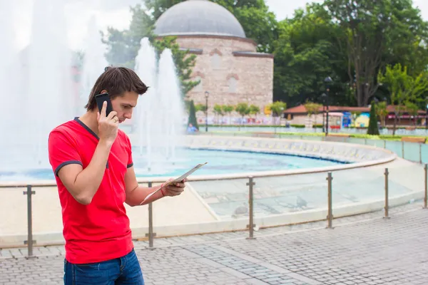 Joven hombre de negocios usando el teléfono con mapa en la ciudad —  Fotos de Stock