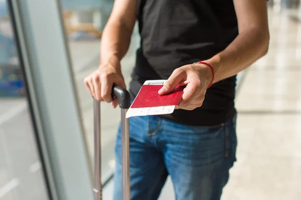 Hombre sosteniendo pasaportes y tarjeta de embarque en el aeropuerto mientras espera el vuelo —  Fotos de Stock