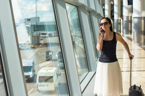 Jovem mulher bonita falando ao telefone enquanto espera pelo voo — Fotografia de Stock