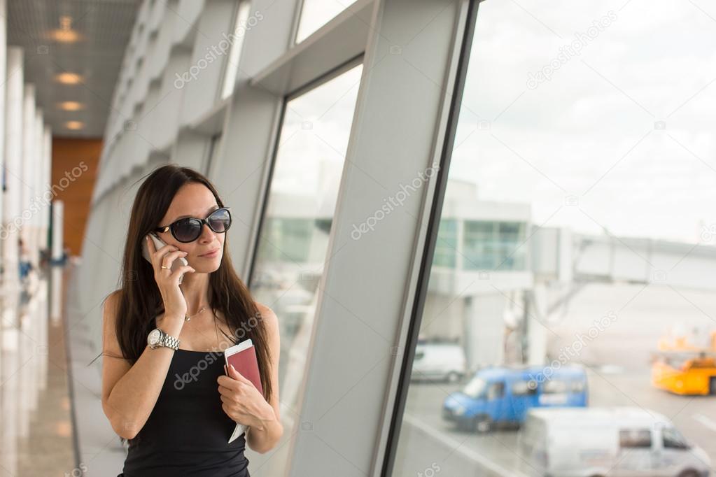 Young woman talking on the phone while waiting boarding