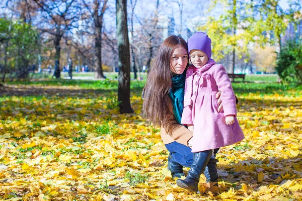 Маленькая девочка и молодая мама в желтом осеннем парке в солнечный день — стоковое фото