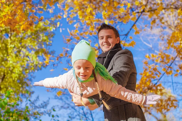 Little girl with happy father having fun in autumn park on a sunny day — Stock Photo, Image
