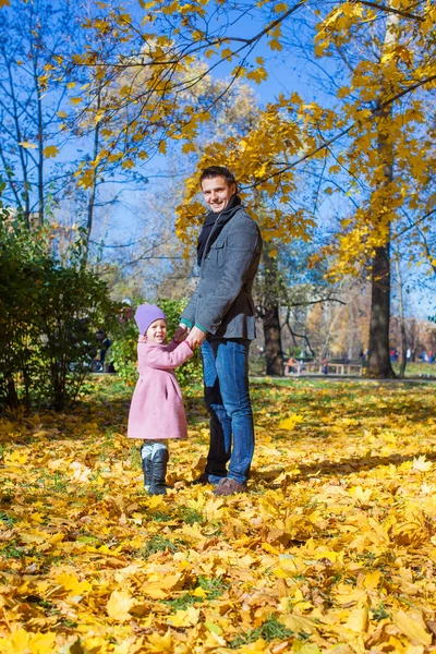 Очаровательная маленькая девочка с счастливым отцом на свежем воздухе в осеннем парке — стоковое фото