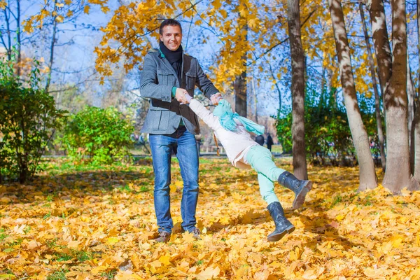Entzückendes kleines Mädchen mit glücklichem Papa, das an sonnigen Tagen Spaß im Herbstpark hat — Stockfoto