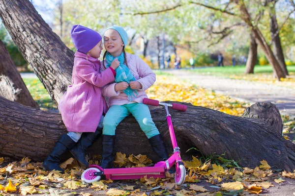 Little beautiful girls with scooter in the autumn park — Stock Photo, Image