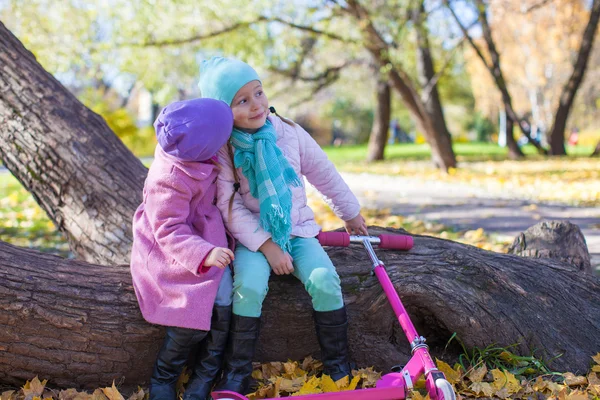 Little adorable girls with scooter in autumn park — Stock Photo, Image