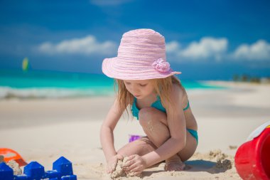 Little girl playing with beach toys during tropical vacation clipart