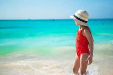 menina bonitinha jogando em águas rasas na praia exótica