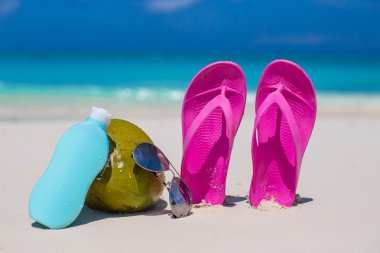 beyaz kum üzerinde flip flop, Hindistan cevizi ve suncream