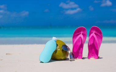beyaz kum üzerinde flip flop, Hindistan cevizi ve suncream