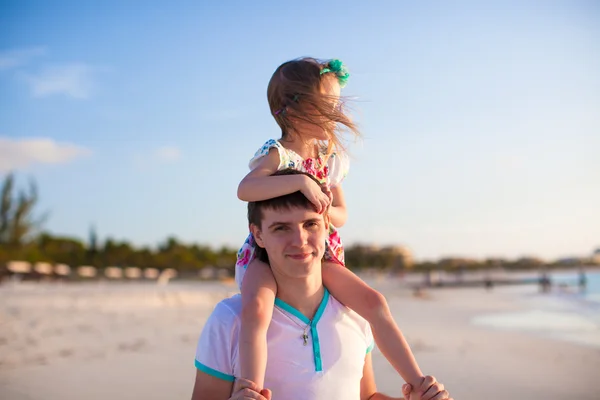 Pequena menina bonito montando em seu pai andando pela praia — Fotografia de Stock