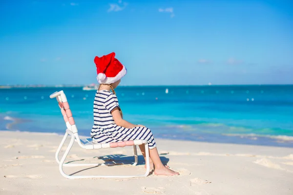 Kleines entzückendes Mädchen mit Weihnachtsmütze am tropischen Strand — Stockfoto