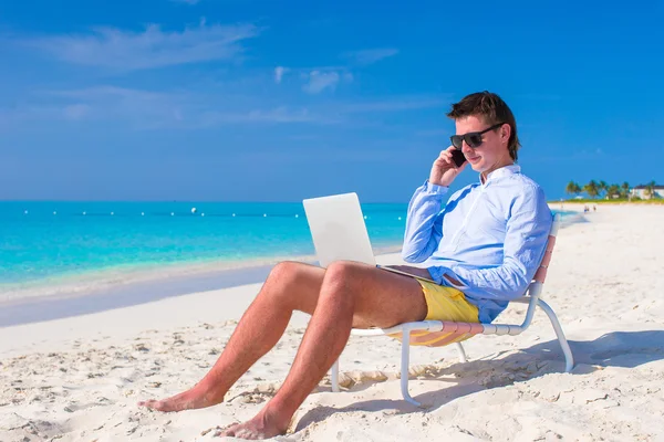 Young man working on laptop at tropical beach — Stock Photo, Image