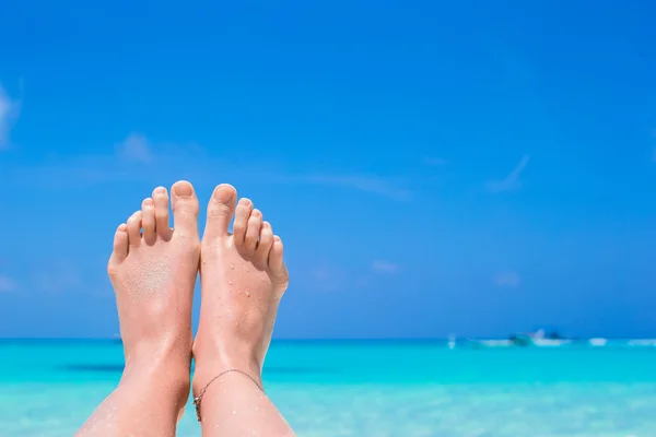 Närbild av kvinnliga fötter på vit sandstrand — Stockfoto