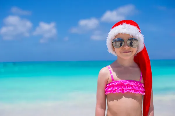 빨간 모자 산타 클라우스를 입은 작고 귀여운 소녀가 해변에서 — 스톡 사진