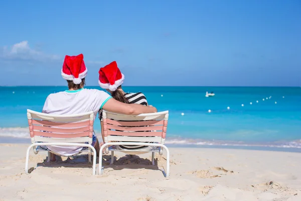 Vista trasera de pareja joven en Santa sombreros disfrutar de vacaciones en la playa —  Fotos de Stock