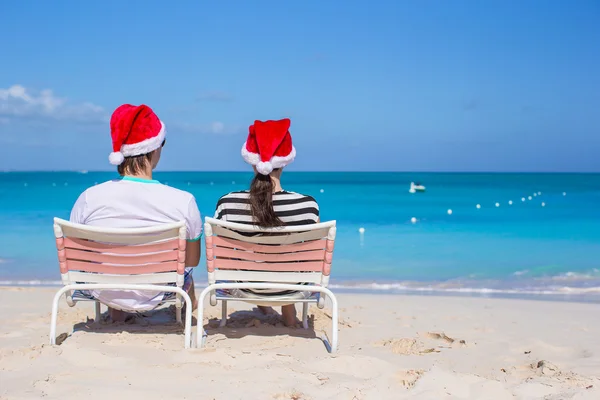 Achteraanzicht van koppel in santa hoeden genieten van strandvakantie — Stockfoto