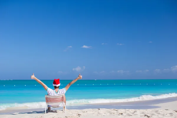 Hombre joven en santa sombrero durante vacaciones en la playa — Zdjęcie stockowe