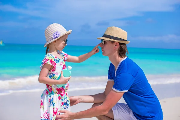 Little girl apply sunscreen on nose of her dad — Stock Photo, Image