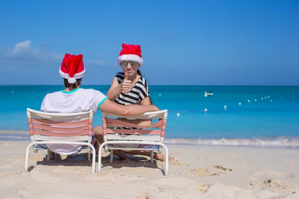 Молодая пара в Санта шляпах во время пляжного отдыха — стоковое фото