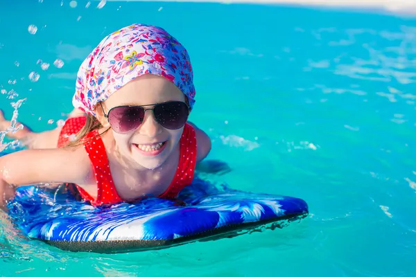 ターコイズ ブルーの海でサーフボードに水泳愛らしい少女 — ストック写真