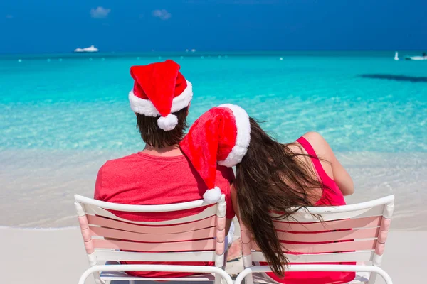 Glückliches romantisches Paar in roten Weihnachtsmützen am tropischen Strand — Stockfoto