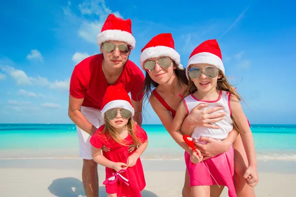 Portret rodziny szczęśliwy w santa kapelusze na plaży — Zdjęcie stockowe