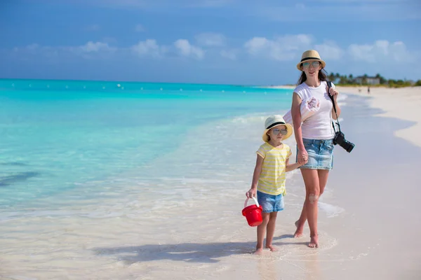 Niña y madre joven con cámara caminando en la playa — Foto de Stock