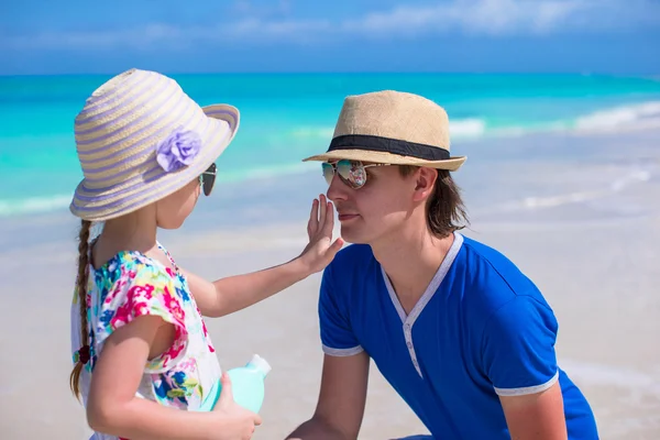 Little girl apply sunscreen on nose of her dad — Stock Photo, Image