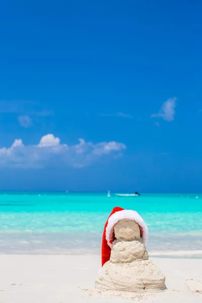 Pequeno boneco de neve arenoso com chapéu de Santa vermelho na praia branca do Caribe — Fotografia de Stock