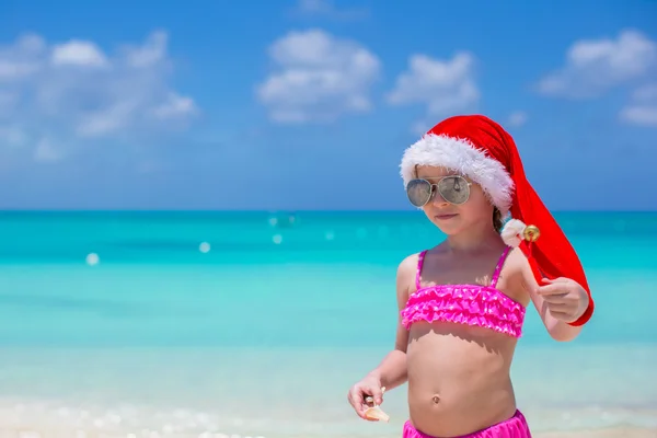 Roztomilá holčička v červeném klobouku santa na tropické pláži — Stock fotografie