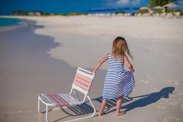 Piccola ragazza carina con sedia in spiaggia durante le vacanze caraibiche — Foto Stock