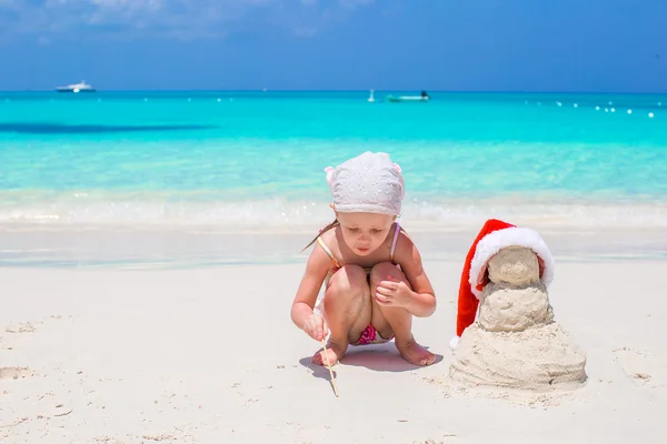 Adorable little girl on seashore with snowman — Stock Photo, Image