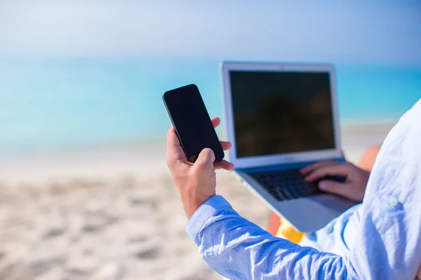Plajda bilgisayar arka plan üzerinde telefon kadar yakın — Stok fotoğraf
