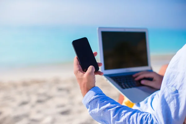 Close up telefon på baggrund af computer på stranden - Stock-foto