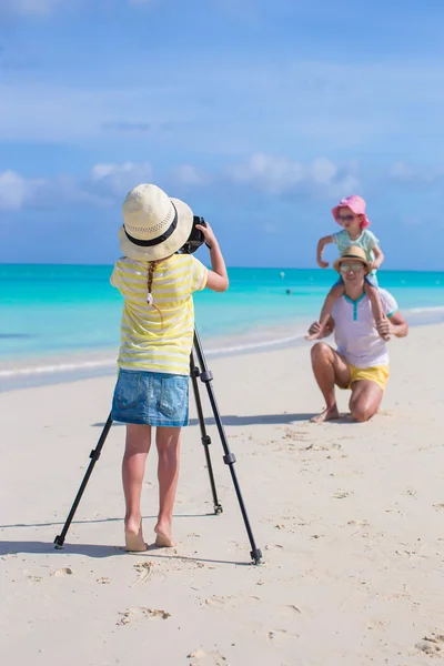 Маленькая девочка фотографирует своего отца и сестру на пляже — стоковое фото